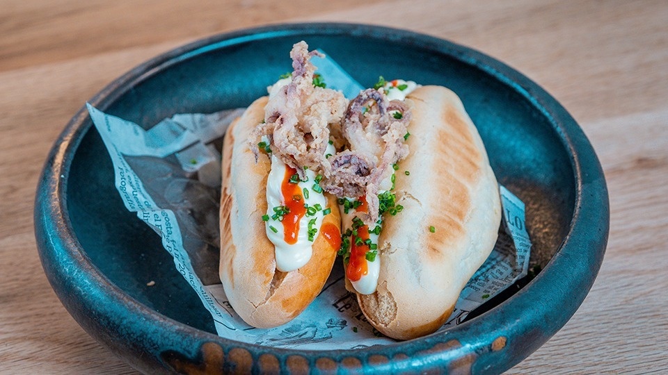 two sandwiches in a bowl with a piece of newspaper on it