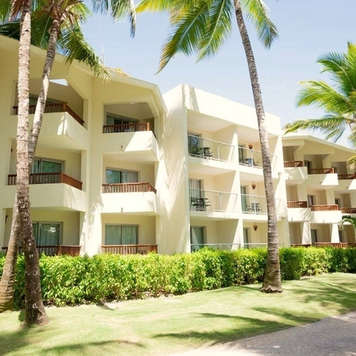 Edificios de habitaciones con balcones entre palmeras y jardín en Impressive Punta Cana