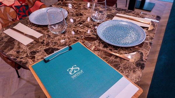 una mesa con platos y cubiertos y un portapapeles que dice sensu