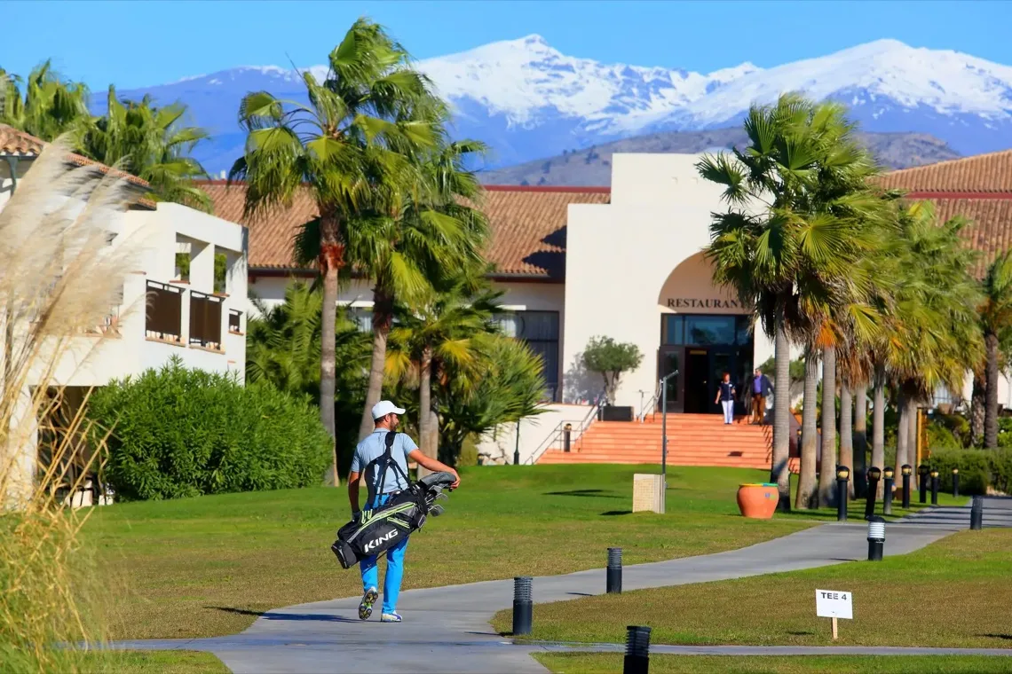 Golfista com o seu saco nos jardins do resort com a Serra Nevada ao fundo