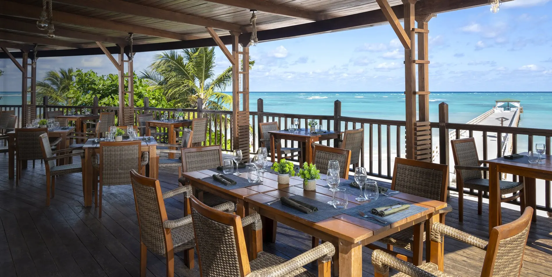 Restaurante con terraza cubierta y mesas de madera frente al mar