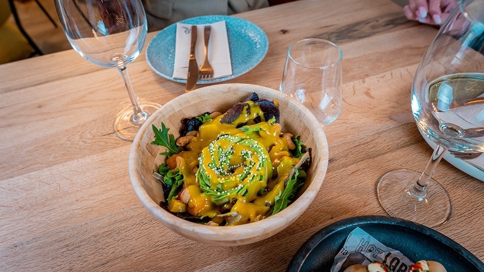 a wooden bowl filled with avocado and sauce on a table
