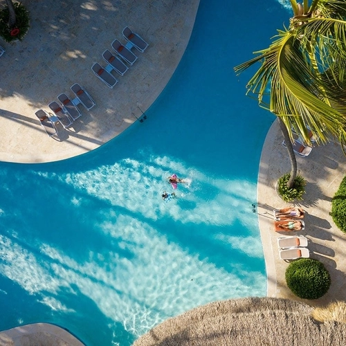 Vista aérea de la piscina con tumbonas y palmeras de Impressive Premium Punta Cana