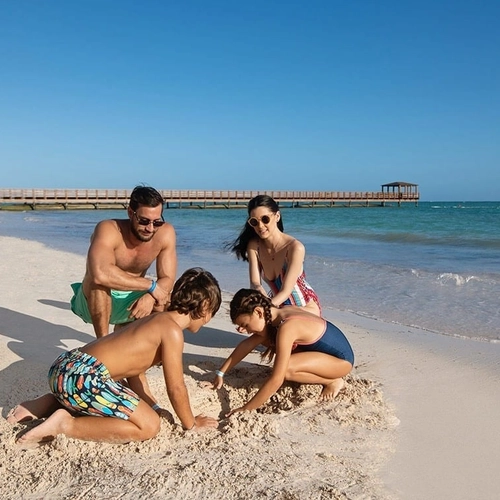 Familia jugando en la arena de la playa de Impressive Punta Cana
