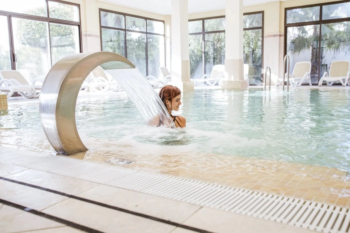 Piscina interior del spa con chorro de agua y tumbonas