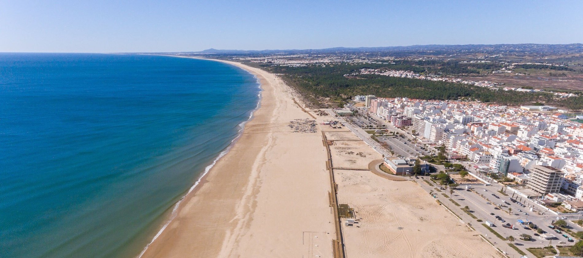 uma vista aérea de uma praia com uma cidade ao fundo