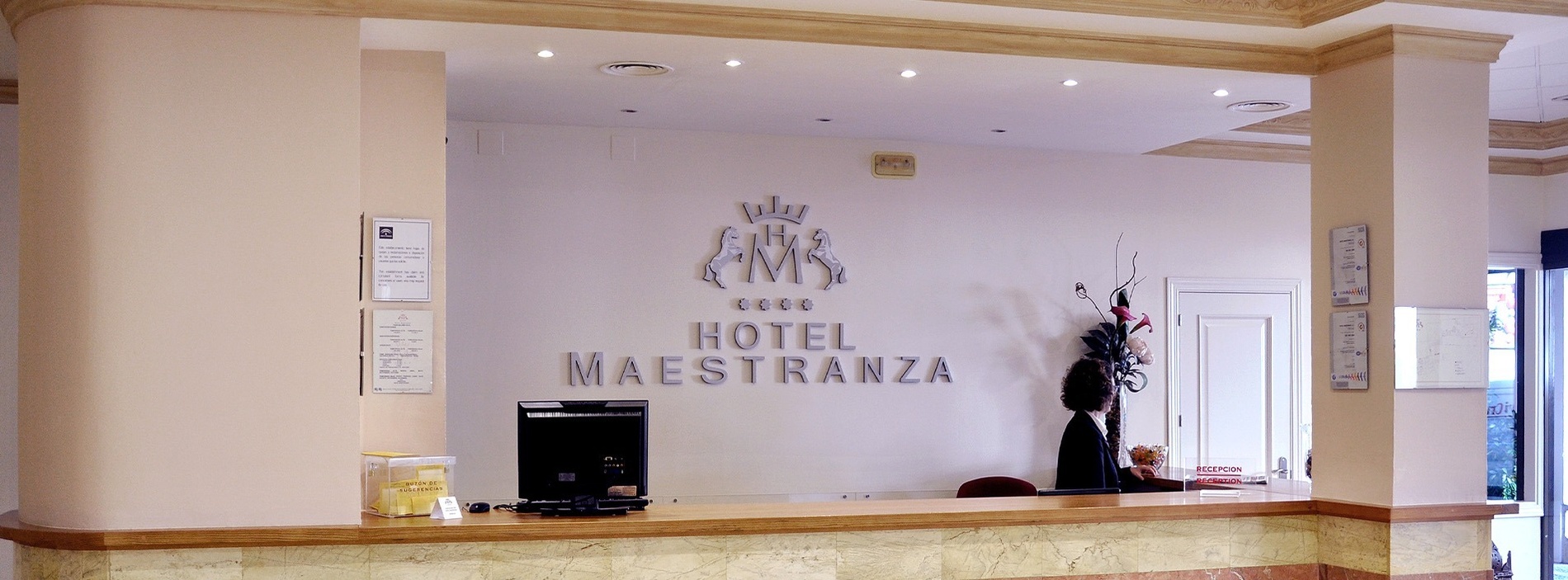 the front desk of hotel maestranza has a computer on it