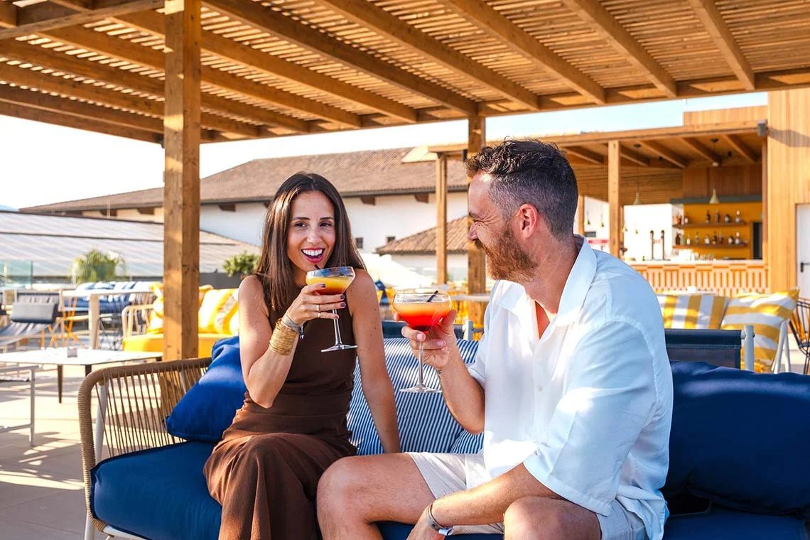 Pareja brindando con cócteles en una terraza del hotel
