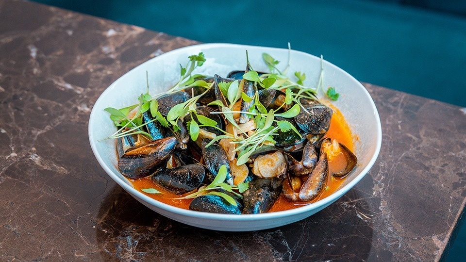 a white bowl filled with seafood and greens on a table