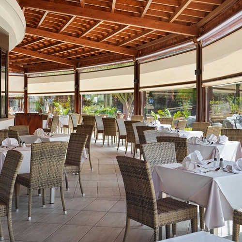 Restaurante con techo de madera, sillas de mimbre y manteles blancos