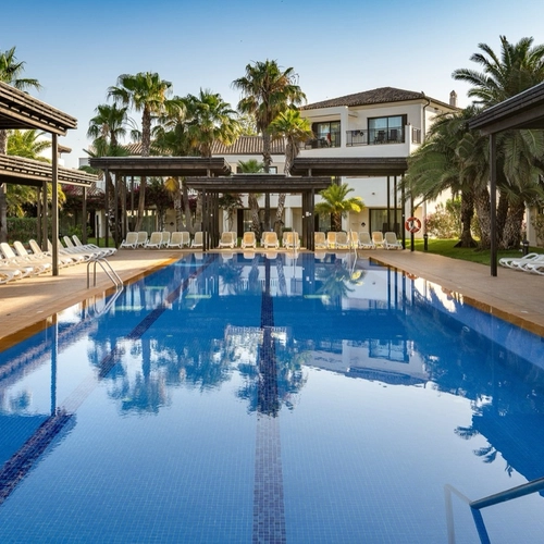Piscina exterior con tumbonas y pérgolas en Impressive Playa Granada Golf