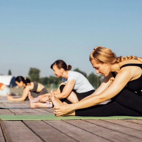 Clase de yoga en una terraza de madera junto al mar