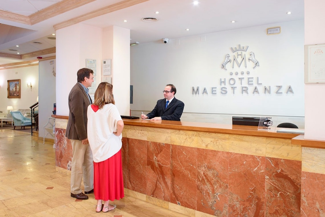 a man and woman are standing at a hotel reception desk