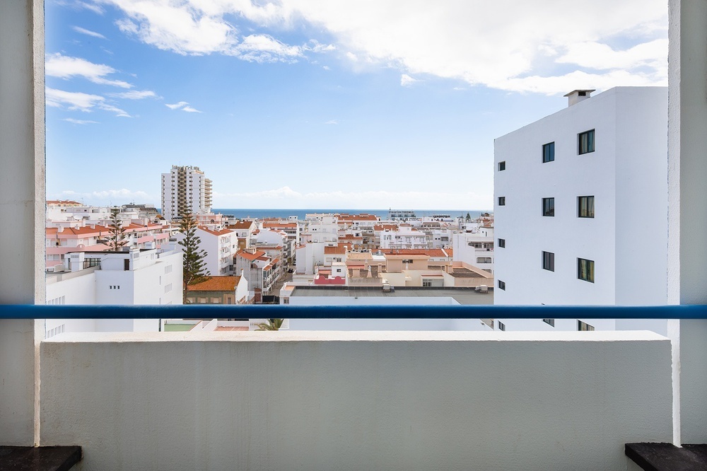 a view of a city from a balcony with a blue railing