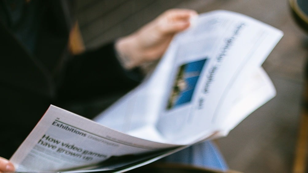 a person is reading a newspaper about exhibitions