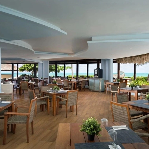 Restaurante de Impressive Premium Punta Cana con mesas de madera y vistas al mar