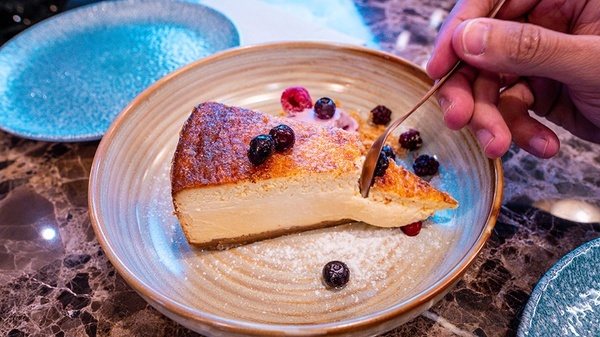 a person is taking a slice of cheesecake from a plate