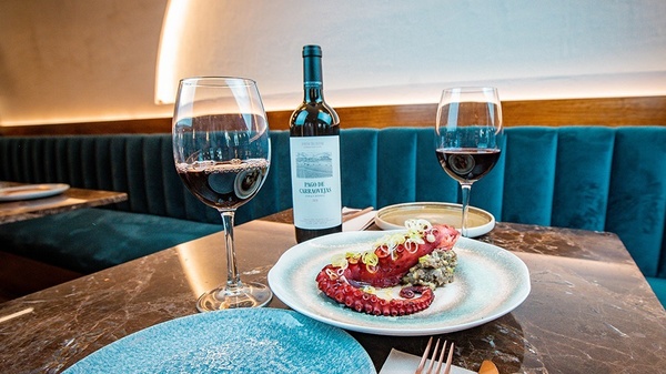 a bottle of paso de garraviers sits on a table next to two glasses of wine