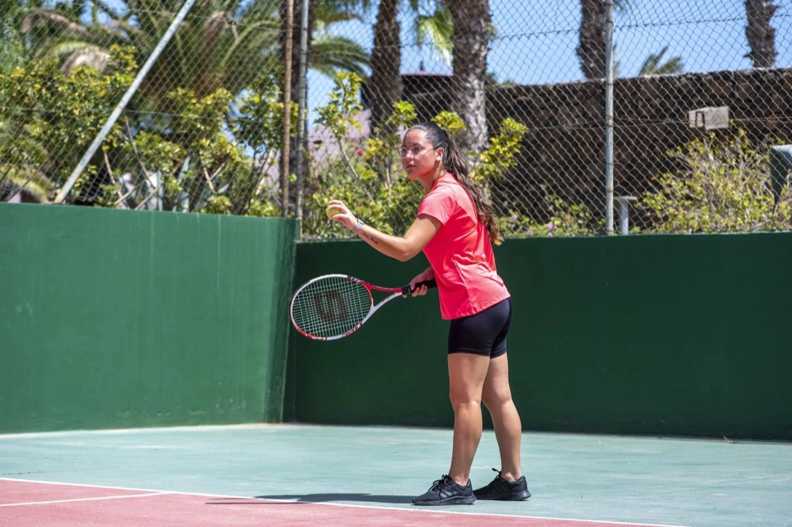 Mulher a jogar ténis num campo do resort