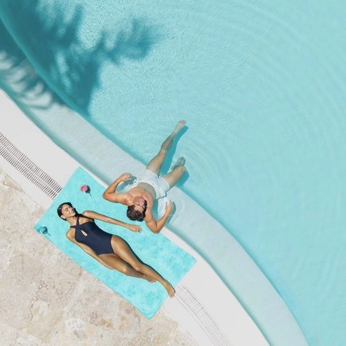Pareja tumbada junto a la piscina, vista desde arriba, en Impressive Premium Punta Cana
