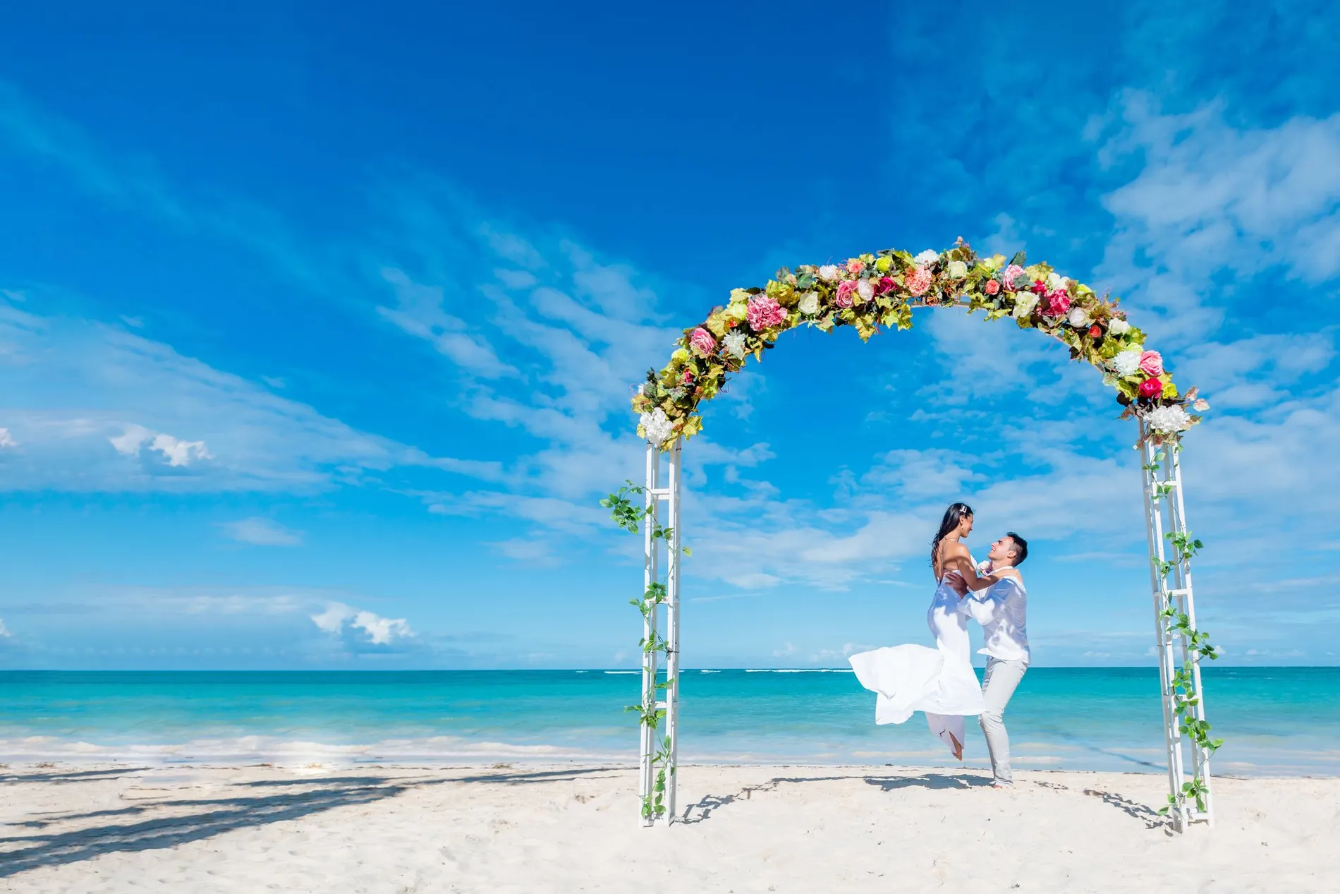 Novios bajo un arco de flores en una playa del Caribe