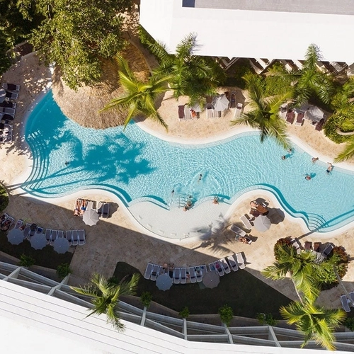 Vista cenital de la piscina entre jardines tropicales de Impressive Premium Punta Cana