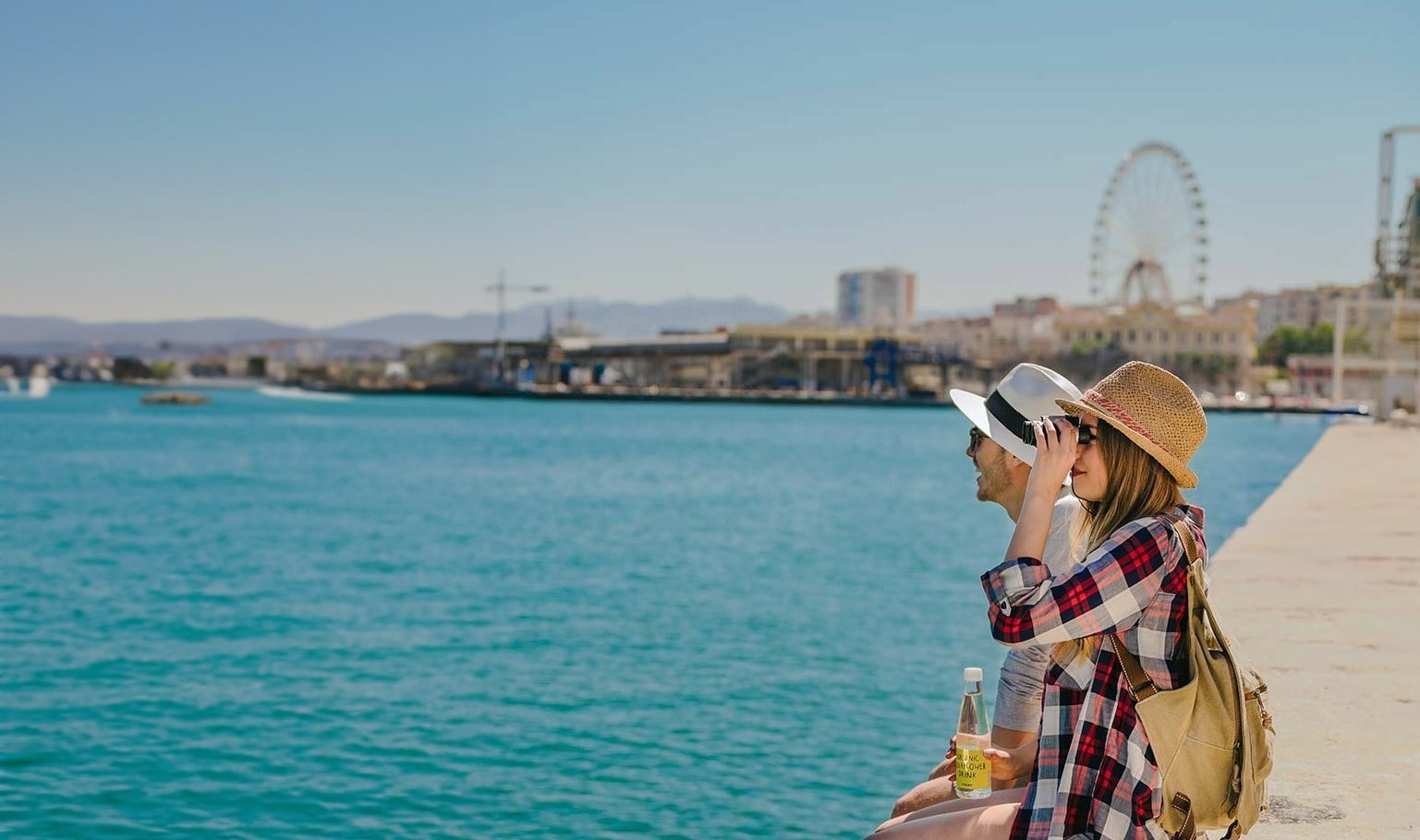 a man and a woman sit on a pier looking at the water