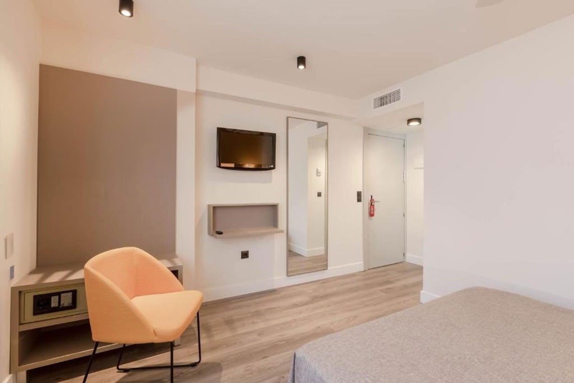 a hotel room with a chair and a flat screen tv