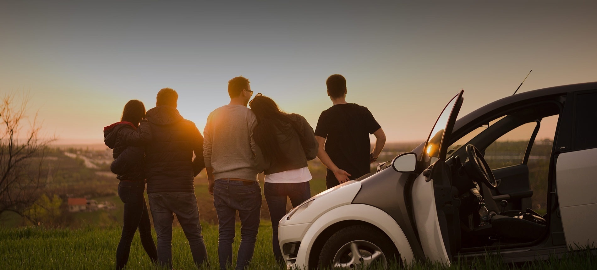 un grupo de personas se paran frente a un coche con la puerta abierta