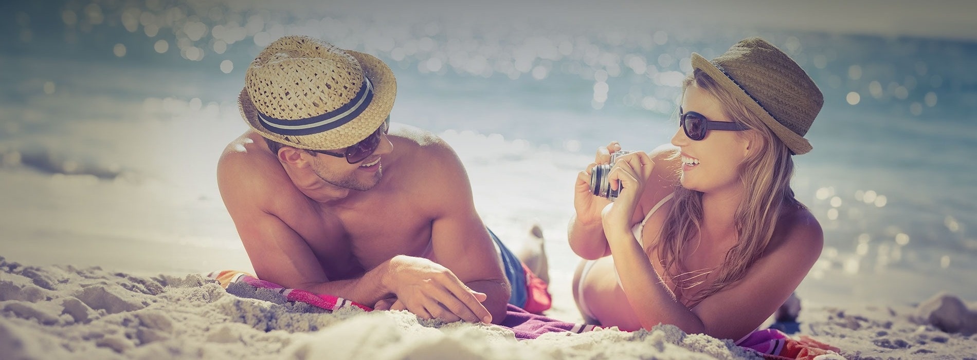 un hombre y una mujer están acostados en la playa y la mujer está tomando una foto