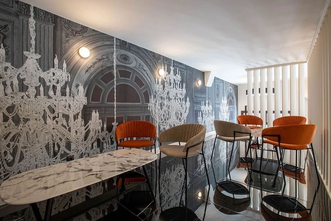 a room with chairs and a table with a chandelier mural on the wall