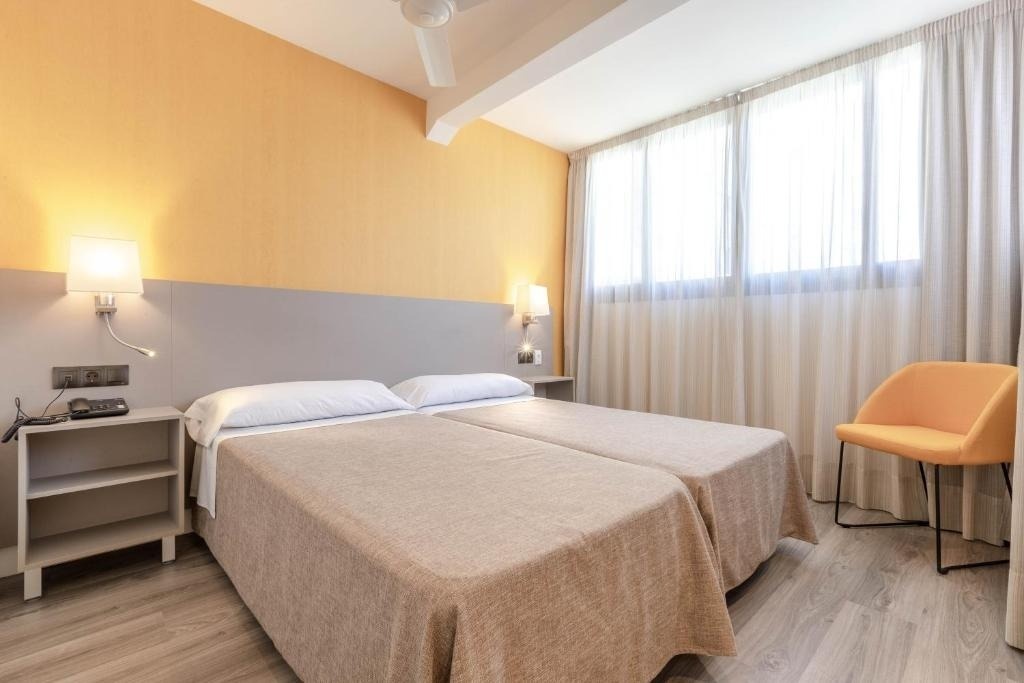una habitación de hotel con dos camas y una silla naranja