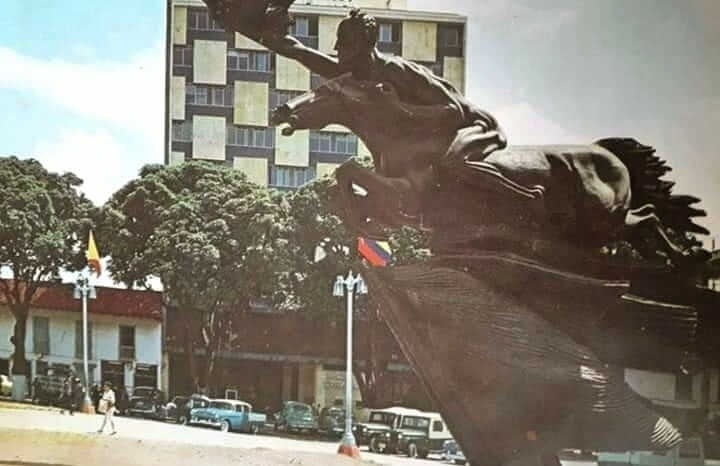 una estatua de un hombre montado en un caballo con un edificio en el fondo .