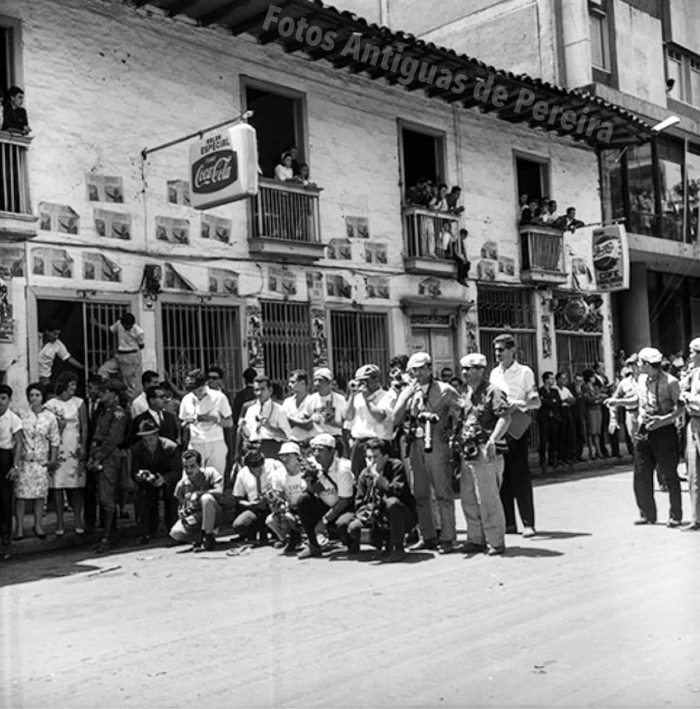 un grupo de personas se paran frente a un edificio con un letrero de coca cola