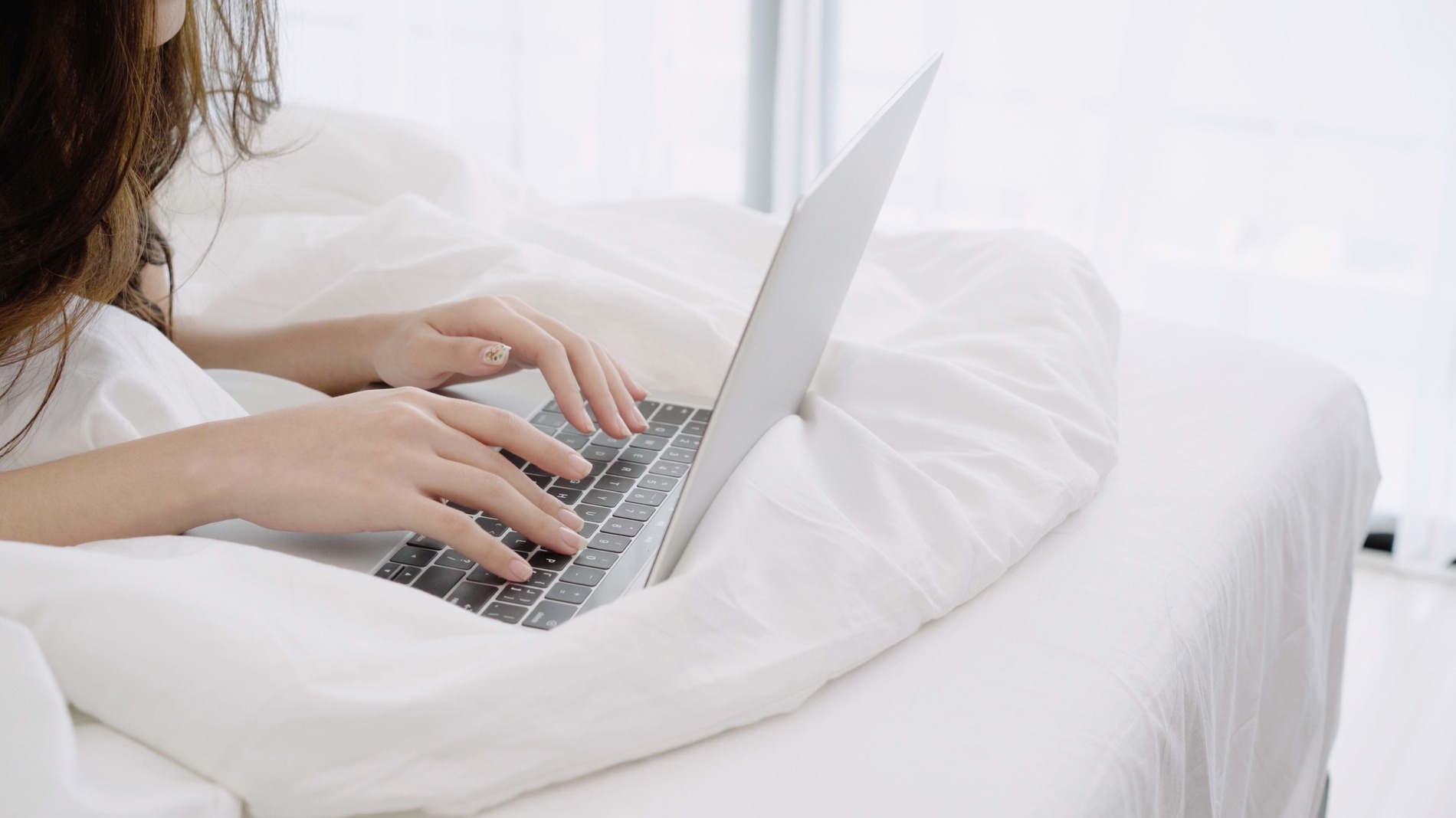 Woman working on laptop in bed at Soratama Torre San Simon.