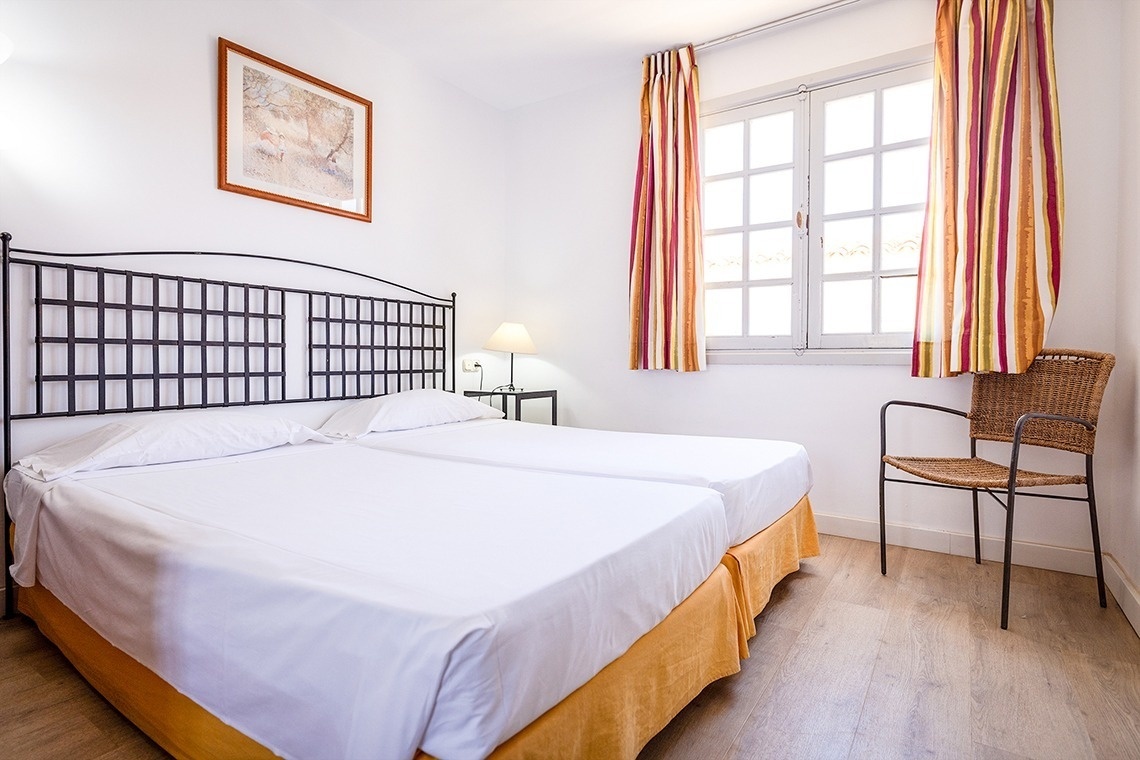 a bedroom with two beds and a wicker chair