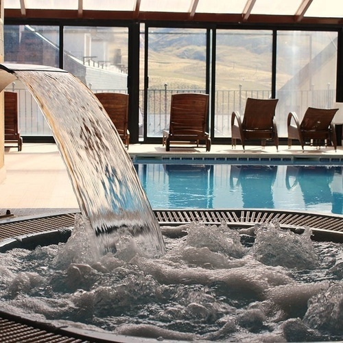 una cascada cae sobre un jacuzzi junto a una piscina