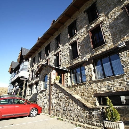un coche rojo está estacionado frente a un edificio de piedra