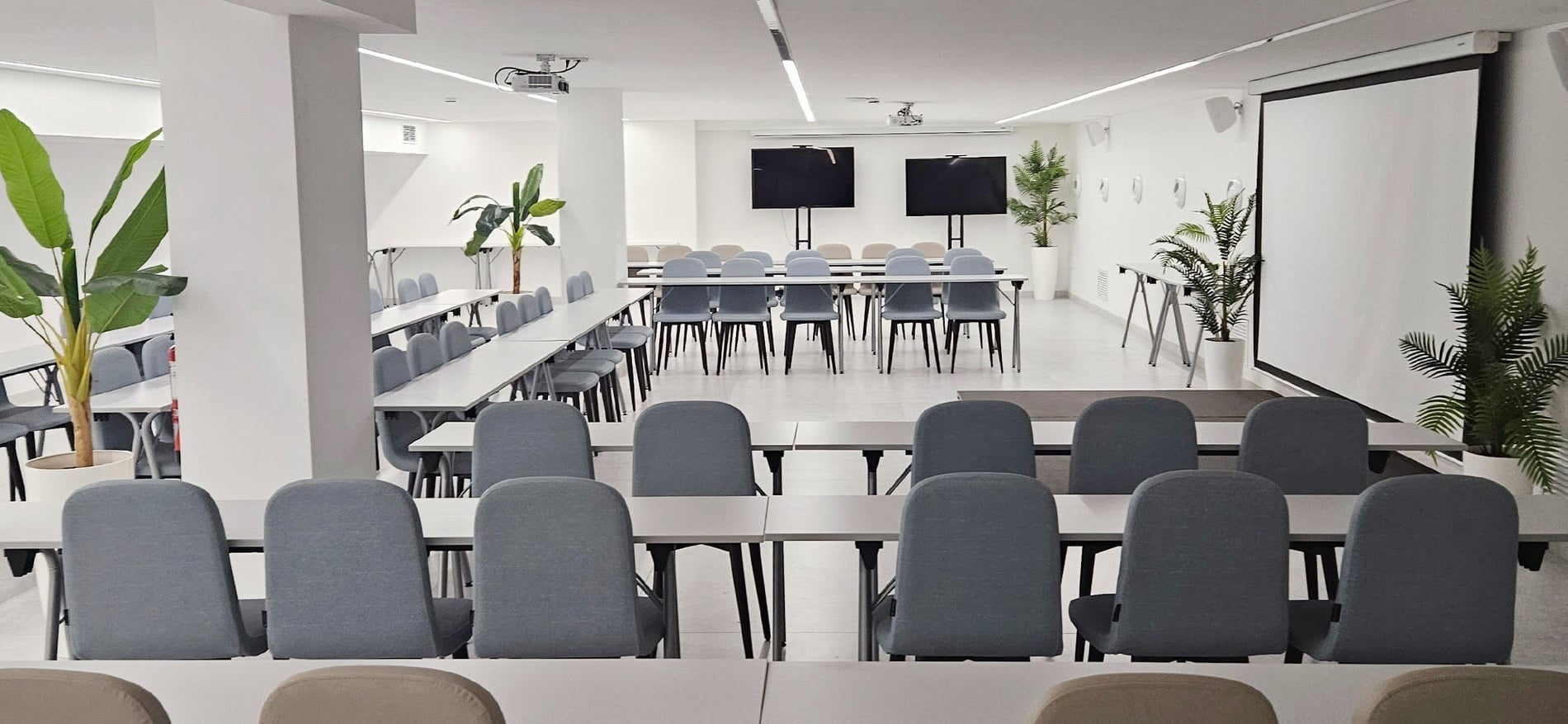 una zona de estar con muebles blancos y plantas en macetas