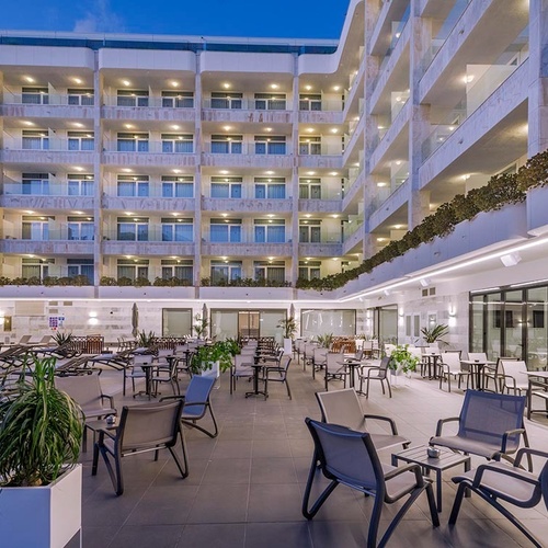 la entrada al hotel olympus palacio está rodeada de palmeras y plantas