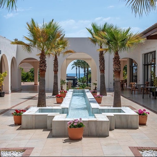 ein Brunnen im Zentrum eines Hofes mit Palmen