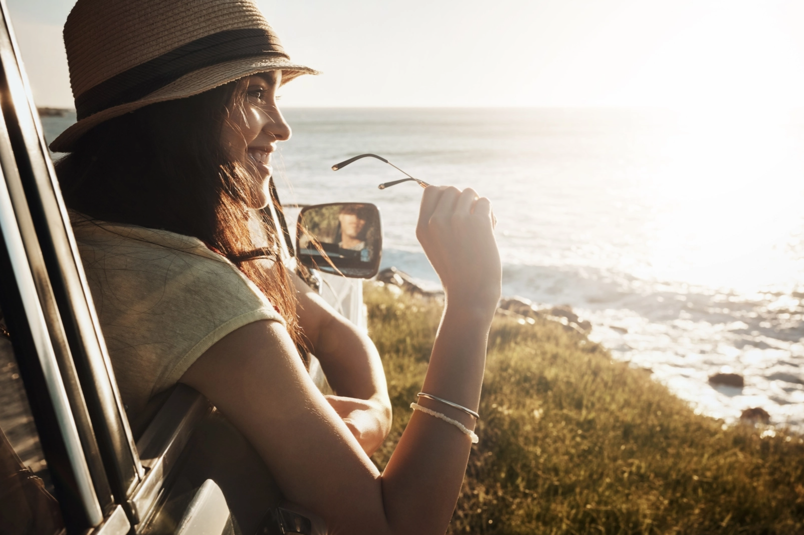Eine Frau schaut aus dem Fenster ihres Autos auf das Meer