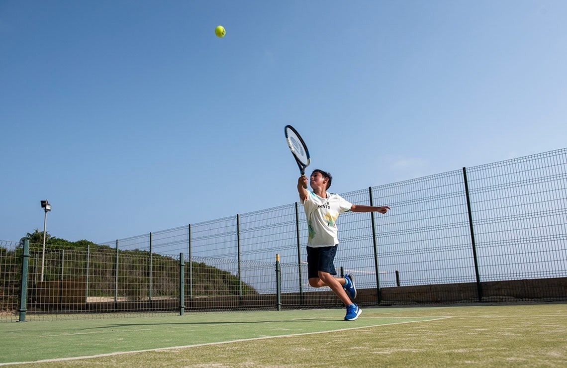 un hombre sostiene una raqueta y una pelota en una cancha de tenis