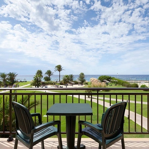 ein Balkon mit zwei Stühlen und einem Tisch mit einer Flasche Wasser darauf
