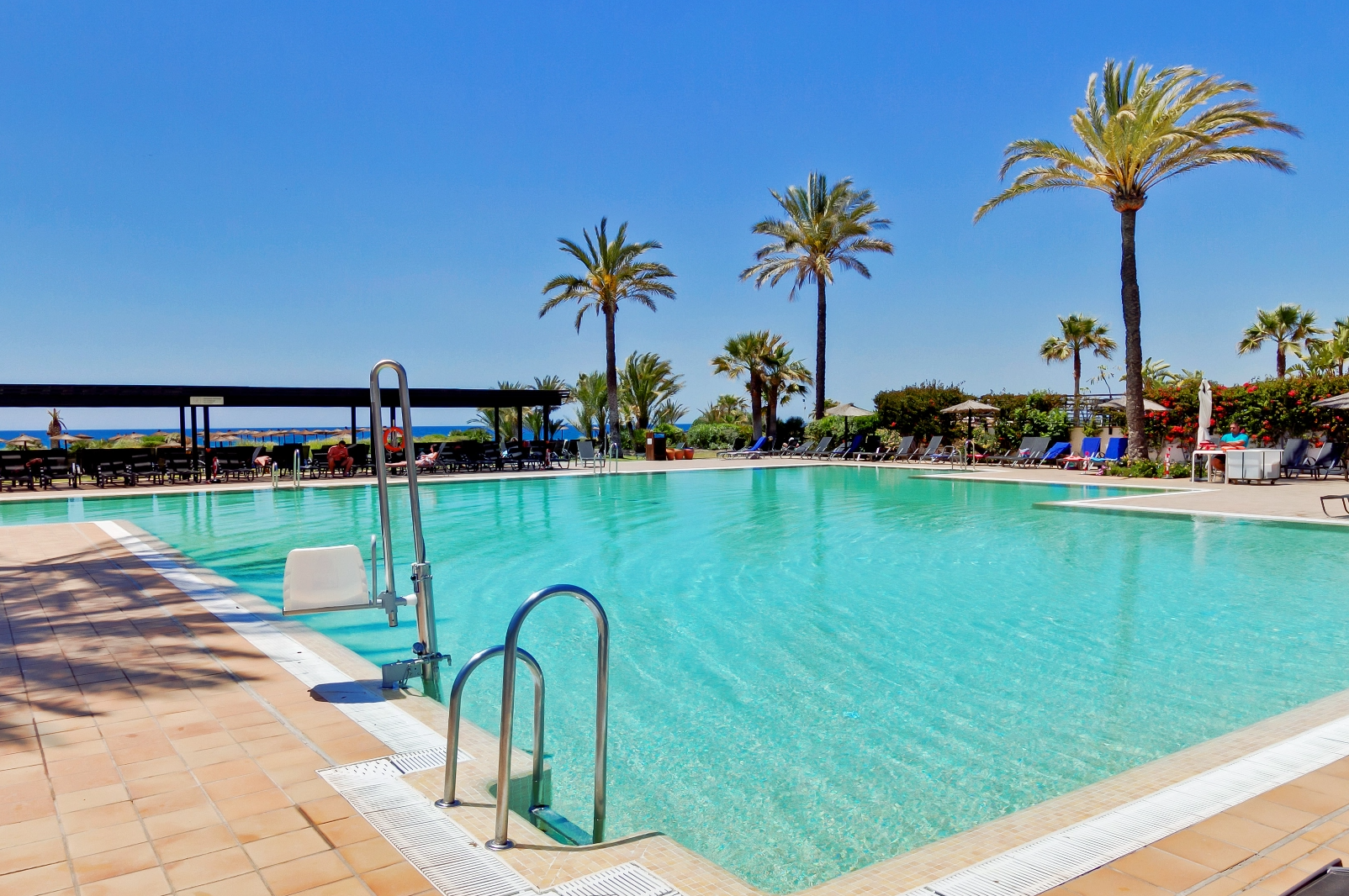 Eine Frau sitzt auf der Motorhaube eines Autos und schaut auf ihr Handy
