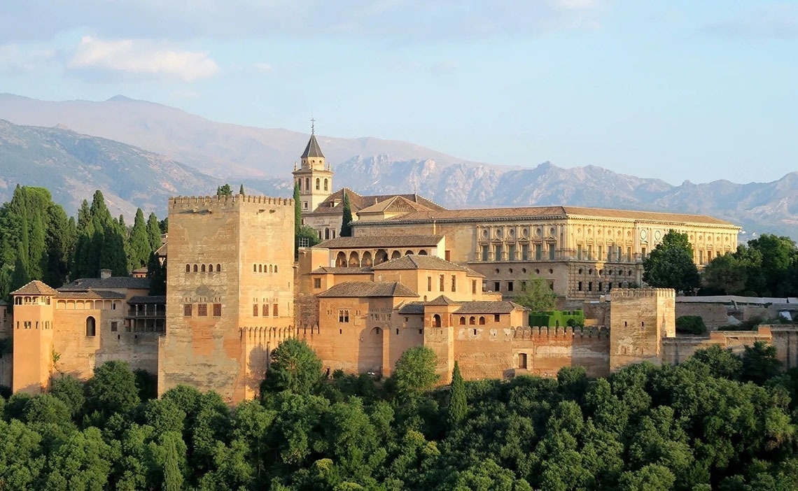 un castillo en medio de un bosque con montañas en el fondo