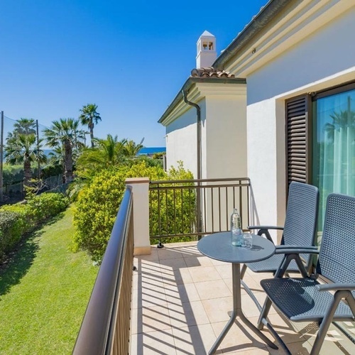 ein Balkon mit zwei Stühlen und einem Tisch mit einer Flasche Wasser darauf