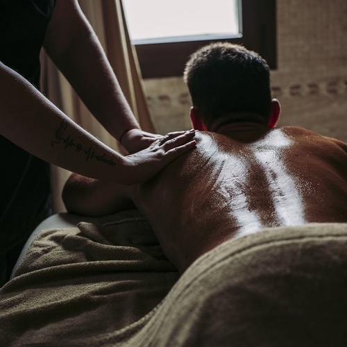 Ein Mann liegt auf einem Bett und bekommt eine Massage