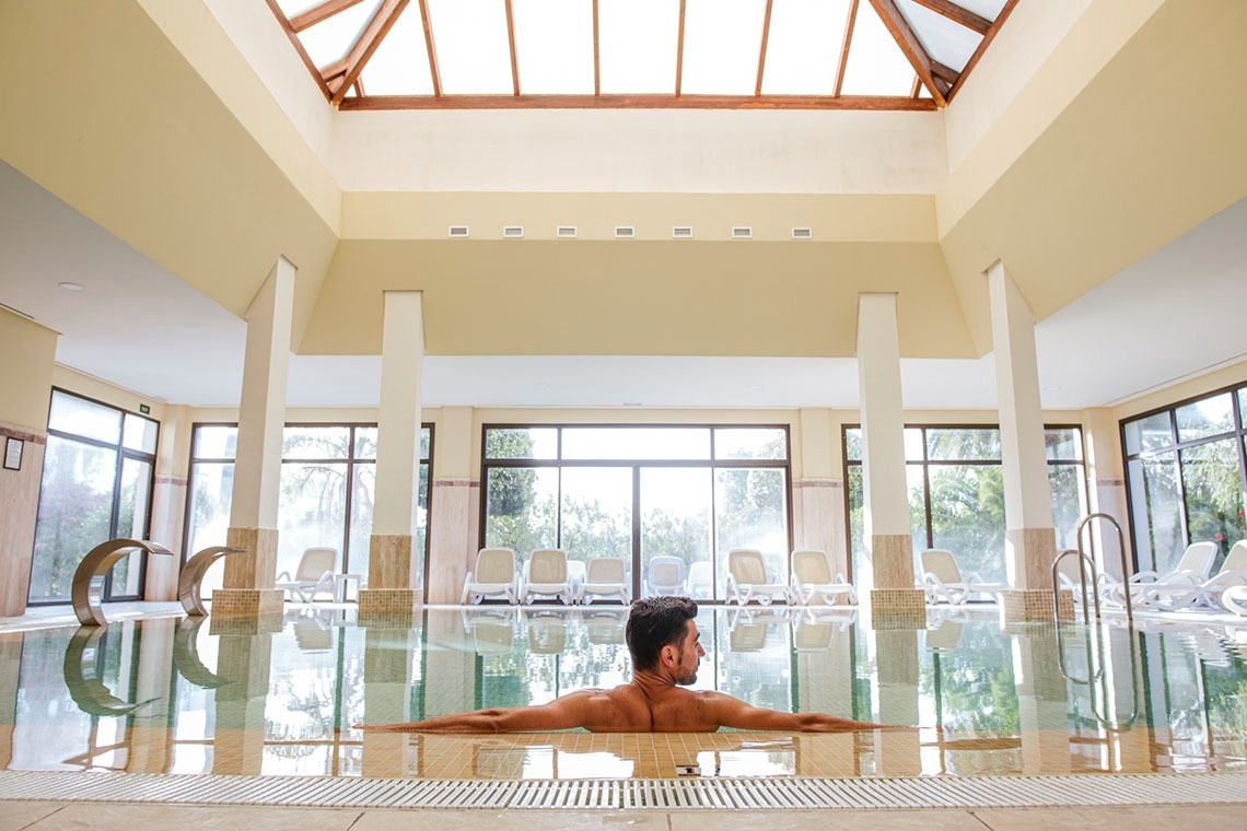 un hombre sostiene una raqueta y una pelota en una cancha de tenis