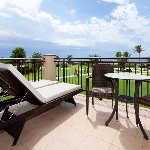 ein Balkon mit zwei Stühlen und einem Tisch mit einer Flasche Wasser darauf